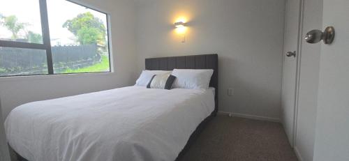 a bedroom with a large white bed with a window at Paradise on Snells Beach in Snells Beach