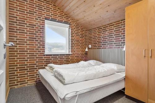 a brick walled room with a bed in a bedroom at 513-Hvide-Sande-Riskrogvej-16 in Havrvig