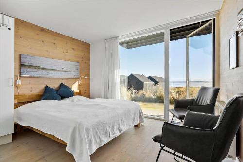 a bedroom with a bed and two chairs and a large window at 731-Hvide-Sande-Slusen-31 in Hvide Sande