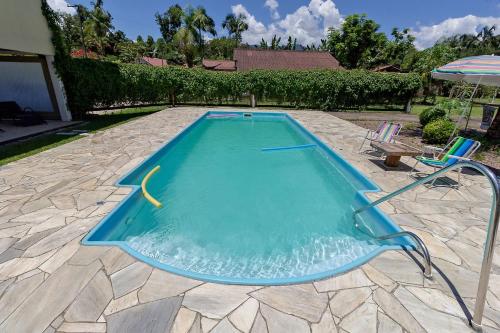 a swimming pool with two chairs and an umbrella at Chácara Recanto do Sossego in Morretes