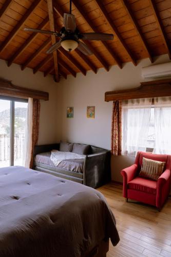 a bedroom with a bed and a couch and a fan at Hacienda Martlot in Ensenada