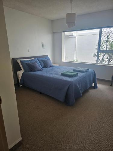 a bedroom with a bed with blue sheets and a window at Wake Up on the Parade in Napier in Napier