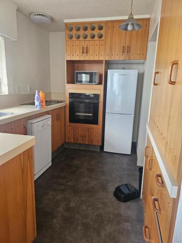 a kitchen with wooden cabinets and a white refrigerator at Wake Up on the Parade in Napier in Napier