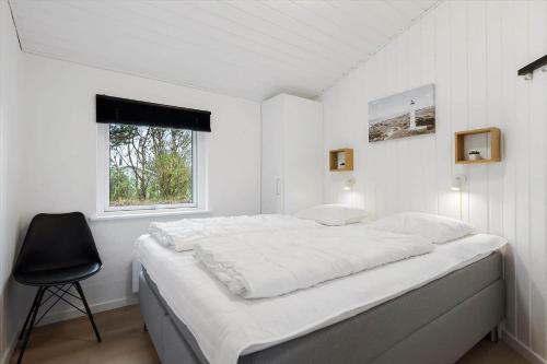 a white bedroom with a large bed and a chair at 354-Hvide-Sande-Fyrmarken-24 in Hvide Sande