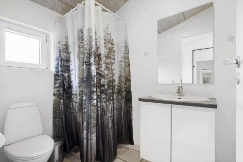 a bathroom with a toilet and a shower curtain with trees at 354-Hvide-Sande-Fyrmarken-24 in Hvide Sande