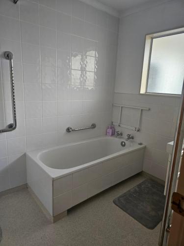a white bathroom with a tub and a window at Wake Up on the Parade in Napier in Napier