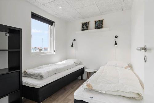 two beds in a white room with a window at 947-Hvide-Sande-Langsand-228 in Hvide Sande