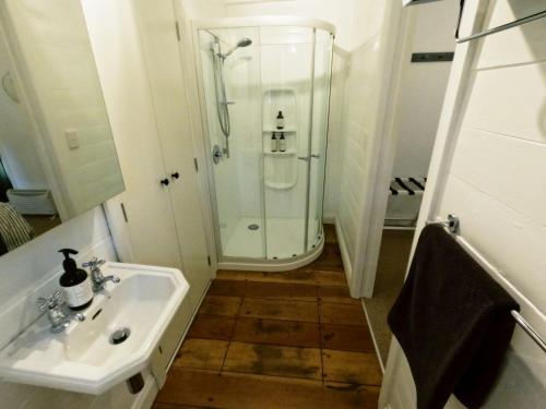 a white bathroom with a sink and a shower at Pinegrove Cottage - Greytown Getaway in Woodside