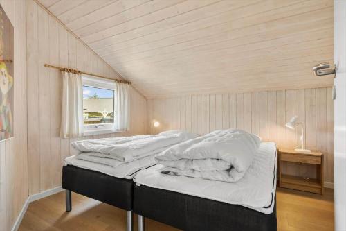 a bedroom with two beds with white sheets and a window at 5526-Hvide-Sande-Baunebjergvej-29-A in Havrvig