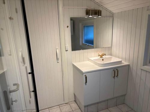a white bathroom with a sink and a mirror at 5526-Hvide-Sande-Baunebjergvej-29-A in Havrvig