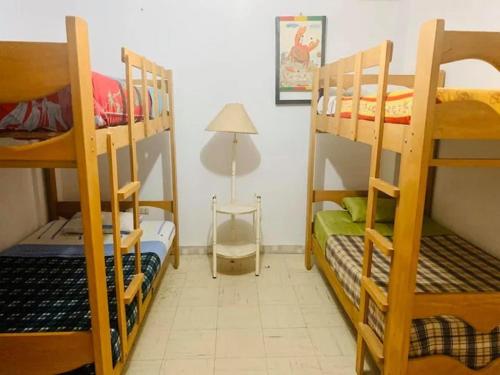 a room with three bunk beds and a lamp at JaimeCrazyhostel in Huarmey