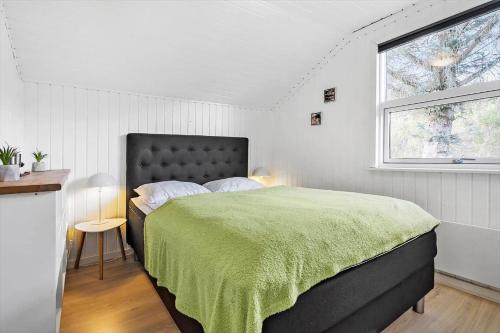 a bedroom with a large bed with a green blanket at 6600-Hvide-Sande-Bjerregaardsvej-128 in Bjerregård