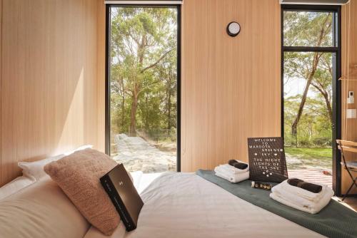 a bedroom with a bed with towels and a window at Maroota Greens SKY by Tiny Away in Maroota