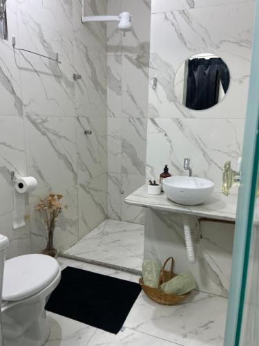 a white bathroom with a sink and a toilet at Cantinho Sol e Sal in Guarapari