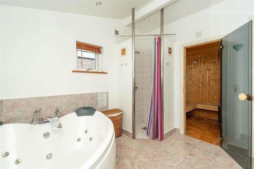 a bathroom with a white tub and a shower at 439-Hvide-Sande-Tingodden-120 in Hvide Sande