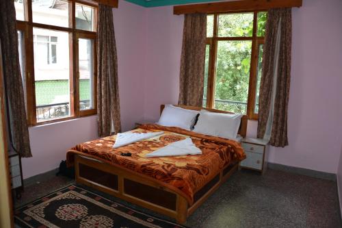 una camera da letto con letto, 2 cuscini e finestre di AbodeHome Cottage a Manāli
