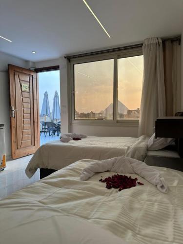 a bedroom with two beds and a large window at sun 3 pyramids view hotel in Cairo