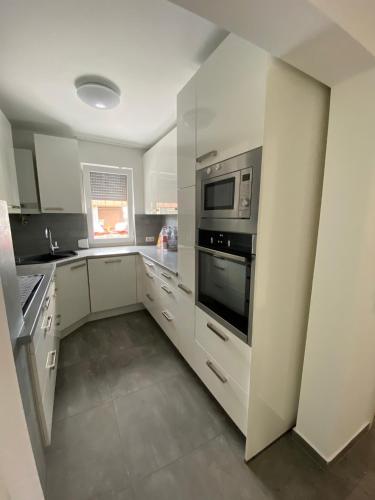 a kitchen with white cabinets and a microwave at HostelCetin in Göppingen