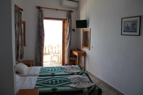 a hotel room with two beds and a window at Hotel Alkyon in Hora Sfakion