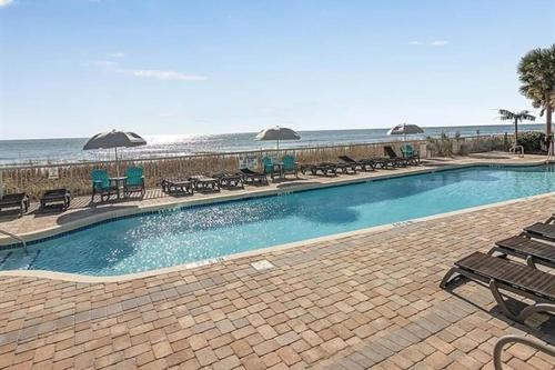 a swimming pool with chairs and umbrellas next to the beach at Huge Ocean Front Condo, Amazing Views in Myrtle Beach