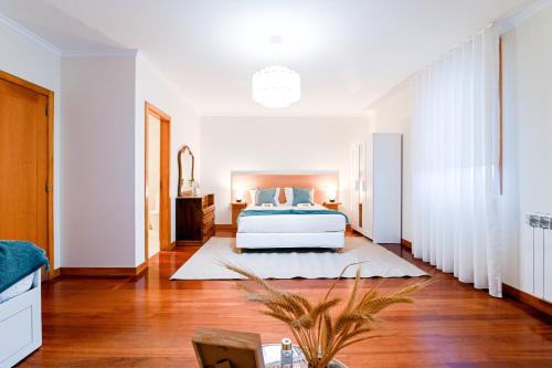a bedroom with a white bed and wooden floors at Casa Tomé de Sousa in Rates