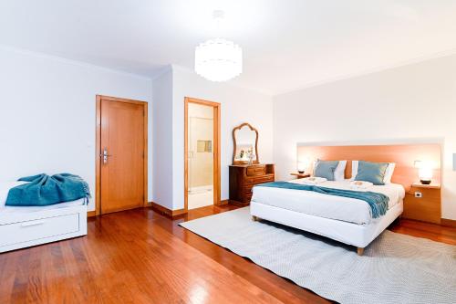 a white bedroom with a bed and a mirror at Casa Tomé de Sousa