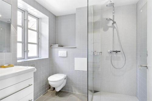 a white bathroom with a shower and a toilet at 6005-Stege-Hjelmvej-15 in Stege