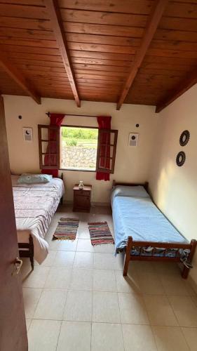 two beds in a room with a window at Casa tafi in Tafí del Valle