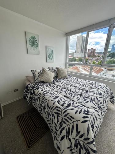 a bedroom with a black and white bed and a window at Edificio león Gallo in Temuco