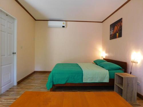 a bedroom with a bed with a green blanket at Swiss Bonihouse Koh Yao Yai in Ban Pru Nai
