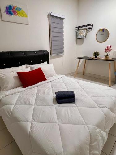 a large white bed with a red pillow on it at AmyHana Cozynest in Putrajaya