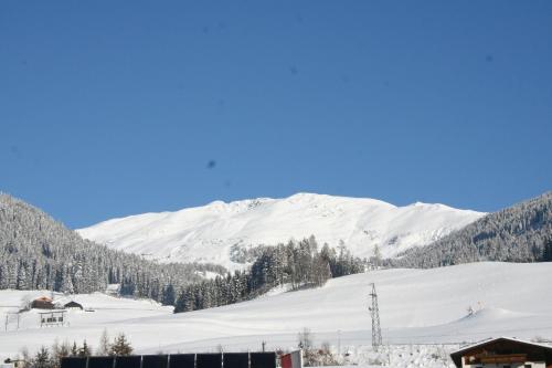 a snow covered hill with a mountain in the background at Haus Mitti in Heinfels