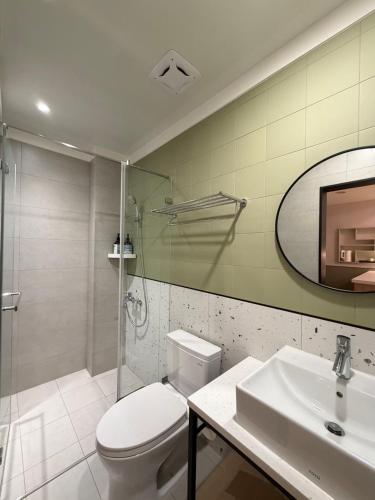 a bathroom with a toilet and a sink and a mirror at 簃居青衖 in Tainan