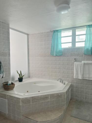 a bath tub in a bathroom with blue curtains at Verano Azul Beachfront Apartment in Isabela in Isabela
