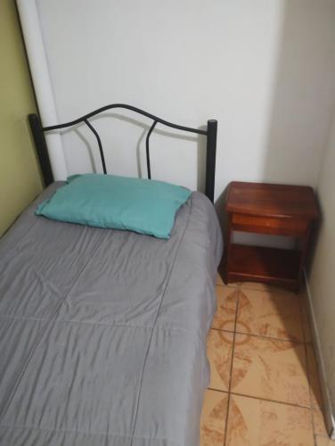 a bed with a blue pillow next to a table at Hostal Claunorte in Calama