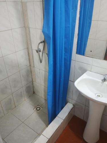 a shower with a blue shower curtain next to a sink at Hostal Claunorte in Calama