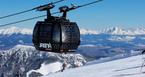 a ski lift flying over a snow covered mountain at Tatralandia Apartmán in Liptovský Mikuláš