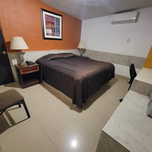 a bedroom with a bed and a table and a chair at hotel villa del sol chihuahua in Chihuahua