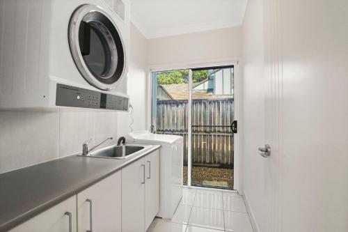 a white kitchen with a sink and a window at Roderick Street 83, Moffat Beach in Caloundra