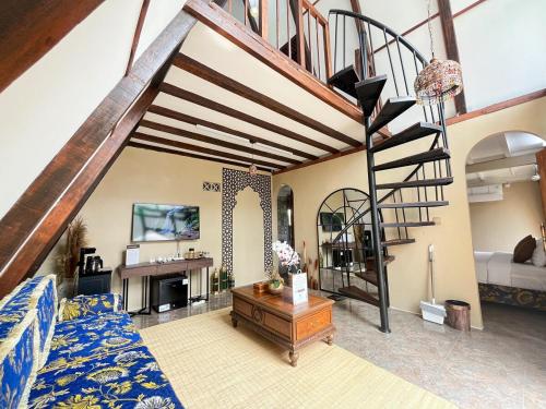 a living room with a blue couch and a spiral staircase at The Phalosaa Villa unit Cabana in Ngaglik
