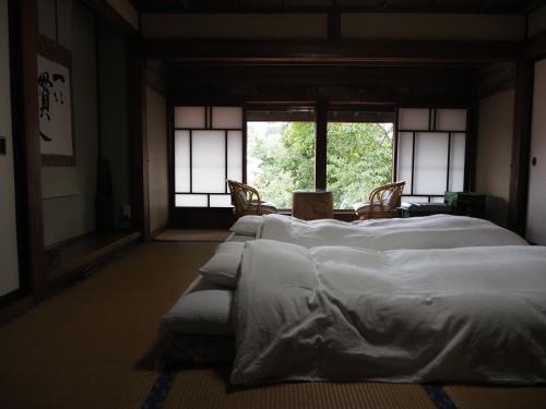 a room with four white beds and a window at OSHI-KIKUYA A Historic Mount Fuji Stay in Fujiyoshida