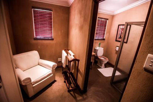 a bathroom with a chair and a toilet at The FarSide Dam Cottage in Nottingham Road