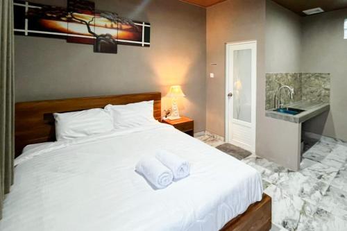 a bedroom with a large white bed with a sink at Pondok Sagara Mitra RedDoorz in Kapal