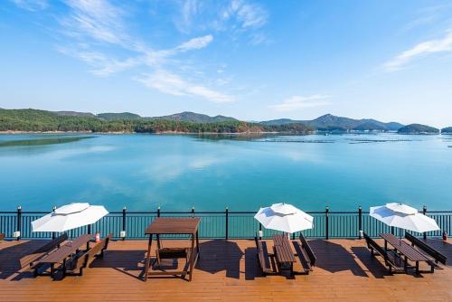 a deck with chairs and a table and umbrellas at Yeosu K-Park Spa Pension in Yeosu
