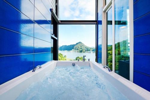a bathroom with a tub with a view of the water at Camp Gate Pension Riverview Spa in Gapyeong
