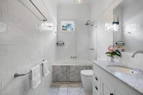 a white bathroom with a toilet and a sink at Paddy's Place in Bangalow
