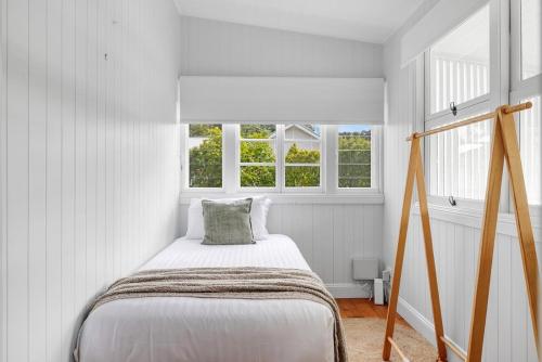a white bedroom with a bed and two windows at Paddy's Place in Bangalow