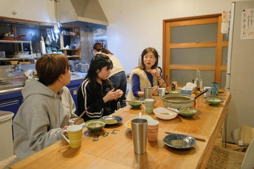 a group of people sitting around a table at Lacomaゲストハウスー海と星空にとけこむ癒しの宿 in Esumi