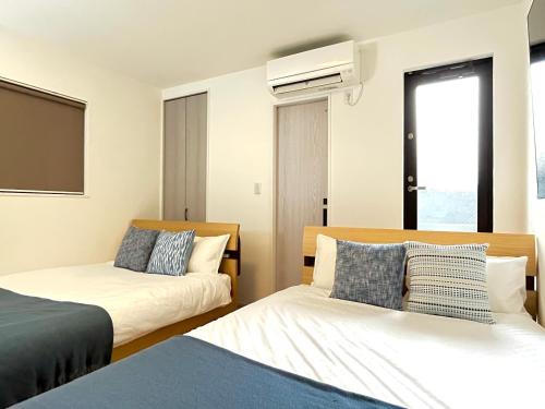 a bedroom with two beds and a air conditioner on the wall at Casa Nishikujo by Liaison in Osaka