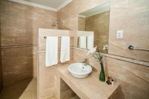 a bathroom with a sink and a vase of flowers at Casa Forno Country Hotel in Otjiwarongo